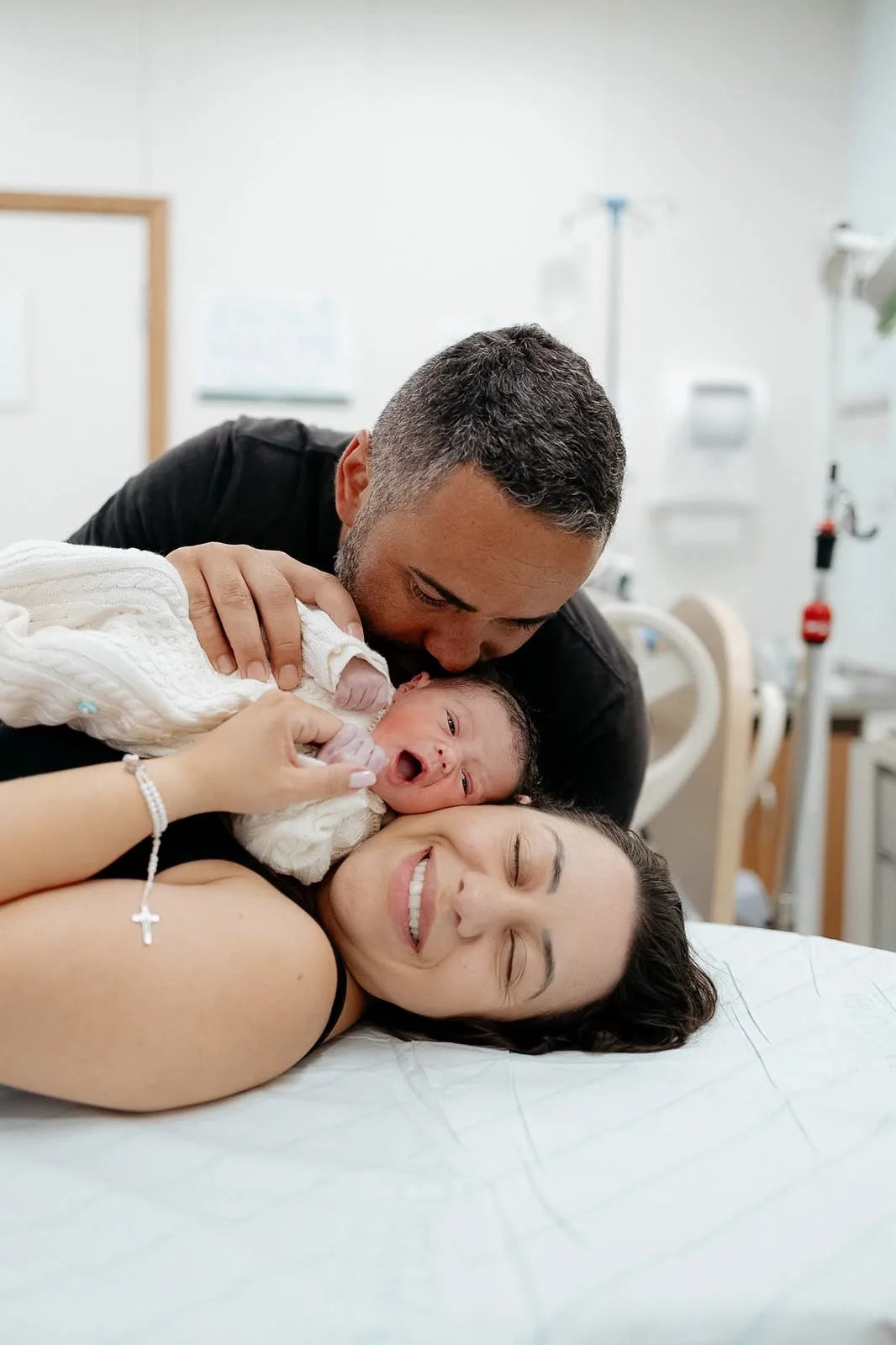 Pai beija a mãe e o bebê recém-nascido no quarto da maternidade