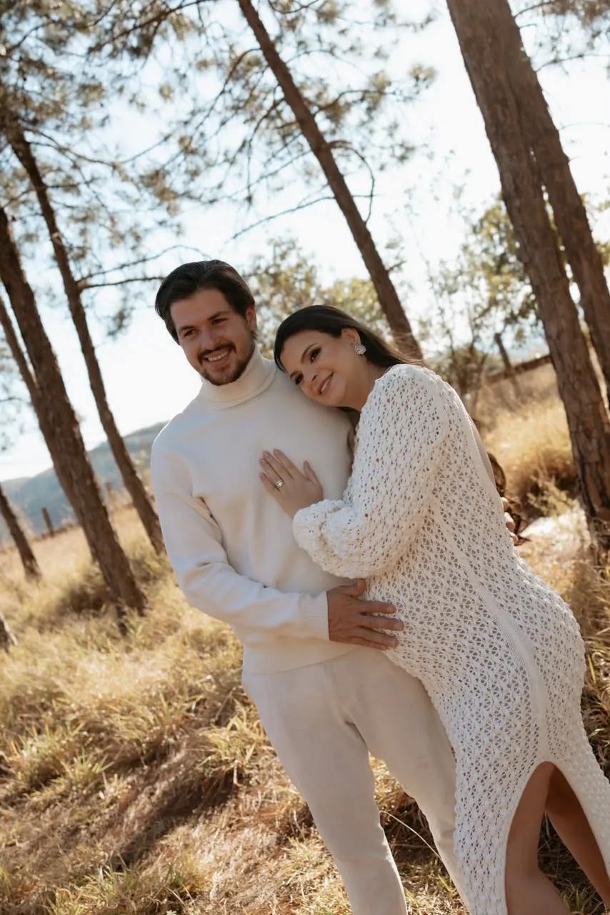 Casal de branco abraçado entre pinheiros